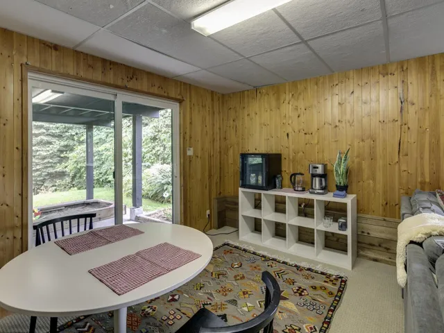 Carpeted dining area with wooden walls and a drop ceiling