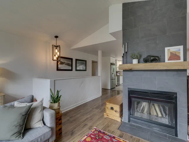 Living area with vaulted ceiling, wood finished floors, and a fireplace