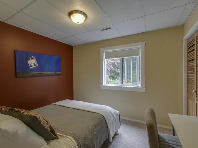 Carpeted bedroom with a drop ceiling and a closet