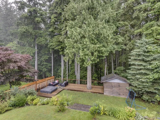 View of grassy yard featuring a deck and a storage shed