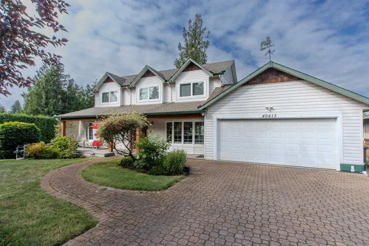 View of front of property with decorative driveway, covered porch, a garage, a front yard, and a shingled roof