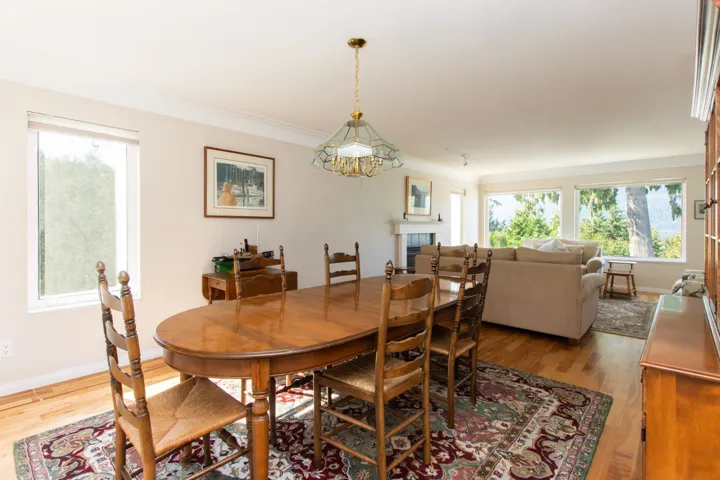 Dining space featuring light wood-style floors, plenty of natural light, a tiled fireplace, and crown molding