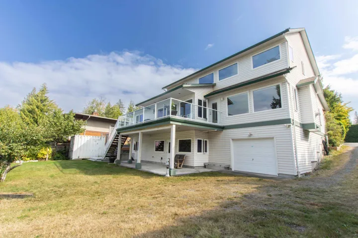 Rear view of house featuring a patio area, stairway, a yard, a garage, and a wooden deck