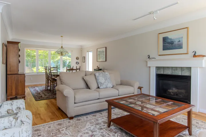 Living room featuring a tiled fireplace, light wood-type flooring, crown molding, a chandelier, and track lighting
