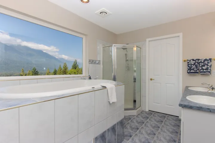Bathroom with a stall shower, a garden tub, double vanity, and dark tile patterned flooring