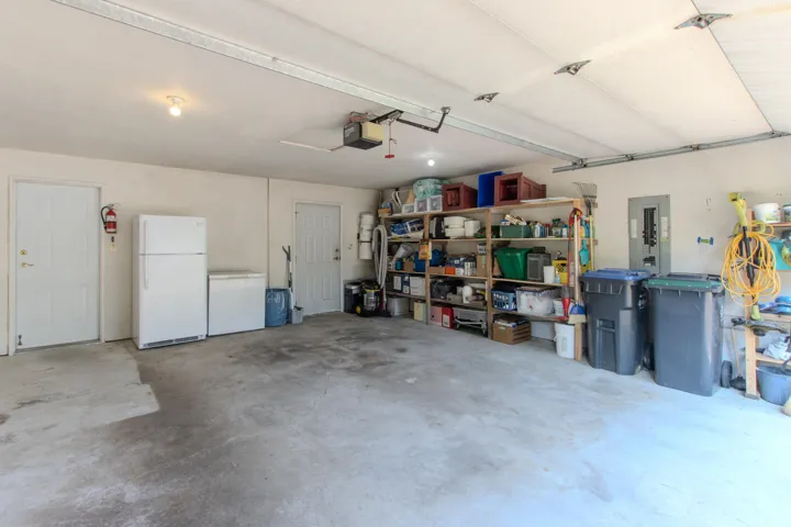 Garage with freestanding refrigerator, electric panel, and a garage door opener