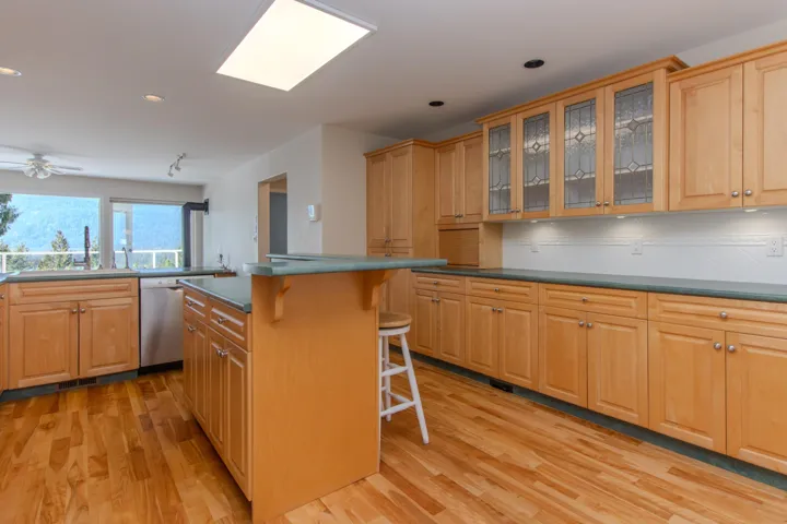 Kitchen with glass insert cabinets, a breakfast bar area, light wood-style flooring, recessed lighting, and dishwasher