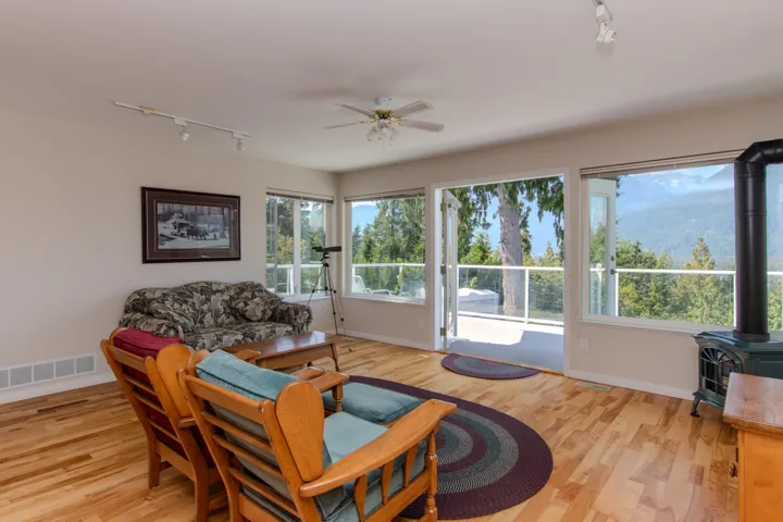 Living room with rail lighting, a wood stove, and light wood-type flooring
