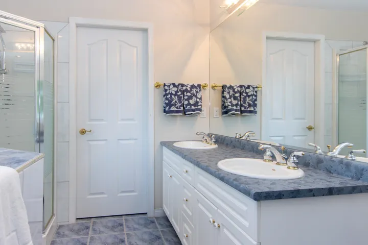 Full bath with a stall shower, double vanity, and dark tile patterned flooring