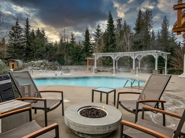 Pool at dusk with a community pool, a pergola, a fire pit, and a patio area