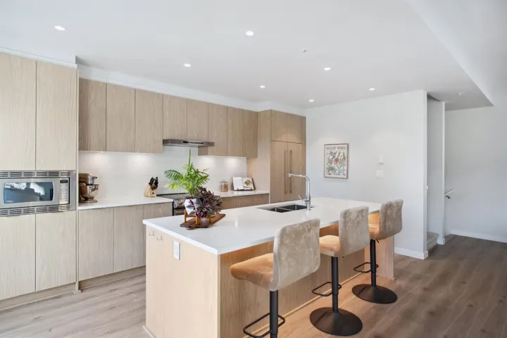 Kitchen with a sink, stainless steel appliances, modern cabinets, a kitchen island with sink, and light countertops