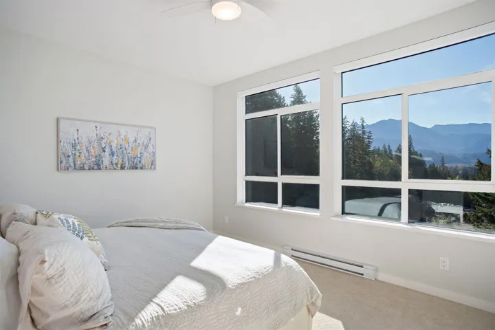 Bedroom featuring baseboard heating, carpet floors, a mountain view, baseboards, and a ceiling fan