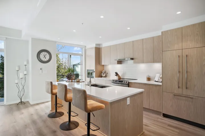 Kitchen with a sink, modern cabinets, stainless steel electric range oven, a kitchen bar, and backsplash