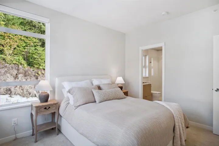 Bedroom with light carpet, baseboards, and ensuite bathroom