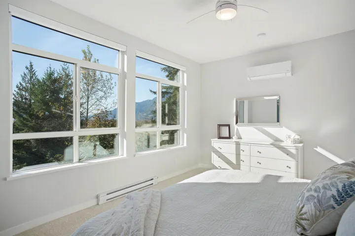 Carpeted bedroom with a baseboard radiator, a wall mounted AC, baseboards, and ceiling fan