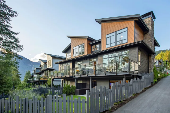 Back of property with a fenced front yard, a balcony, a mountain view, and a chimney