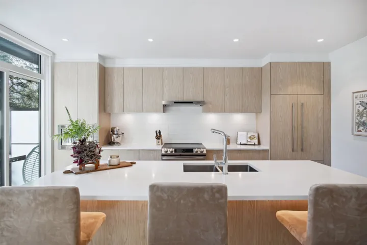 Kitchen featuring a sink, modern cabinets, stainless steel range with electric cooktop, light countertops, and a breakfast bar area
