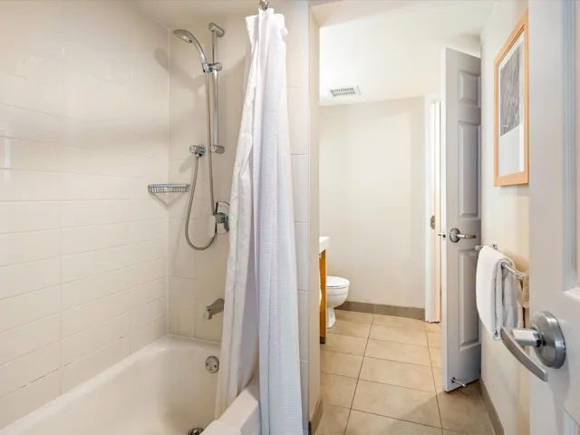 Bathroom featuring shower / bath combo with shower curtain, light tile patterned floors, and vanity