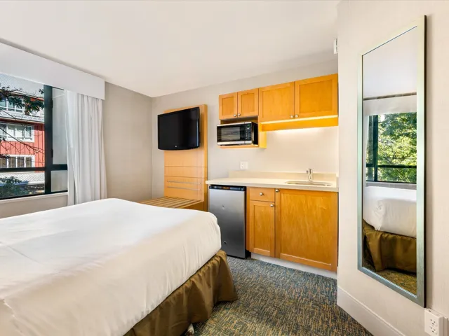 Bedroom featuring multiple windows, stainless steel refrigerator, and dark colored carpet