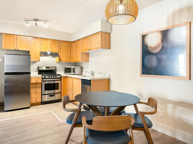 Kitchen with light countertops, appliances with stainless steel finishes, light wood-type flooring, under cabinet range hood, and pendant lighting