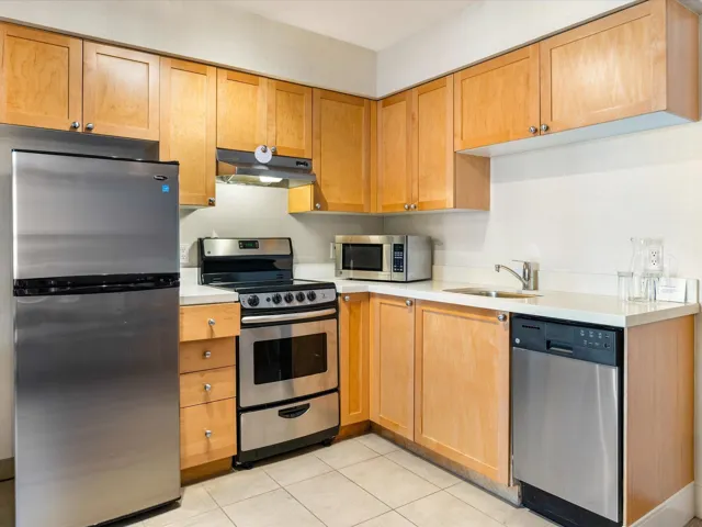 Kitchen with appliances with stainless steel finishes, light tile patterned floors, and under cabinet range hood