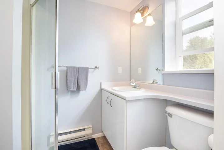 Bathroom featuring toilet, a baseboard heating unit, a stall shower, vanity, and tile patterned flooring
