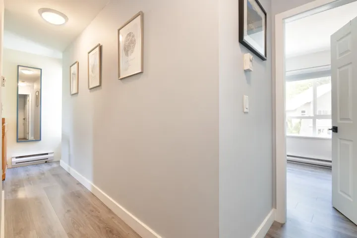 Hallway featuring light wood-style flooring, a baseboard heating unit, and baseboards