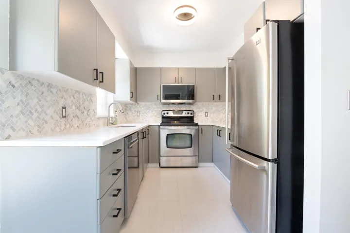 Kitchen with appliances with stainless steel finishes, gray cabinets, a sink, and tasteful backsplash