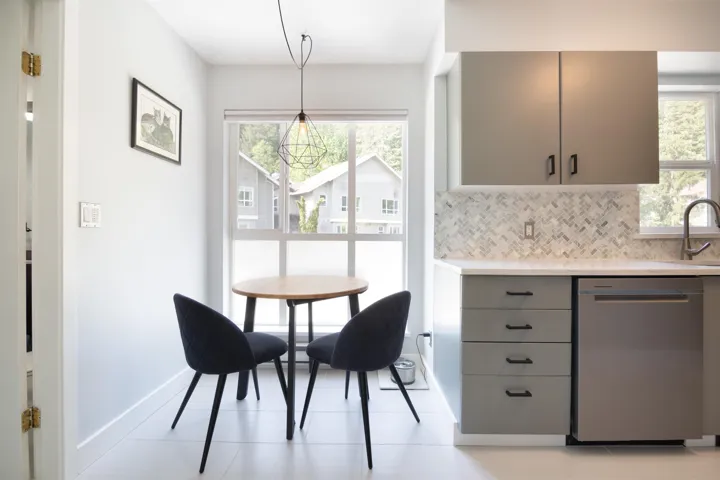 Kitchen with backsplash, gray cabinets, light countertops, stainless steel dishwasher, and a sink
