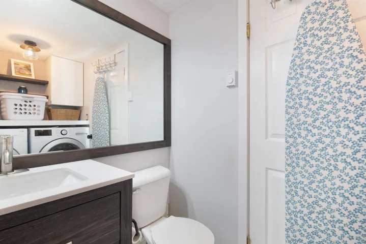 Bathroom featuring toilet, washer / clothes dryer, and vanity