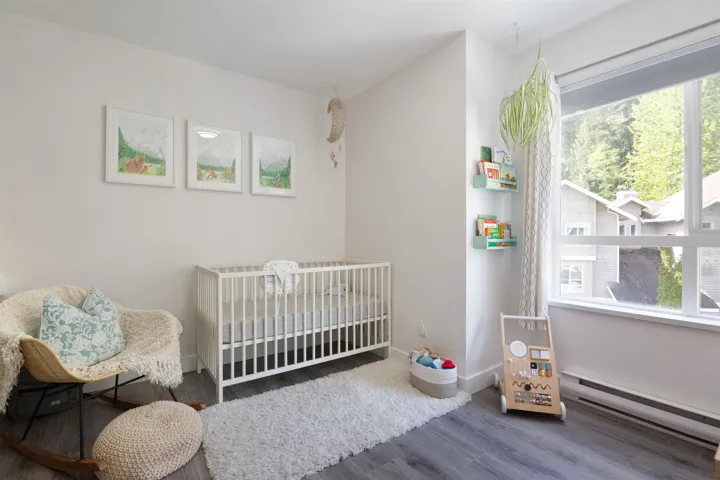 Bedroom featuring a baseboard radiator, a crib, baseboards, and wood finished floors