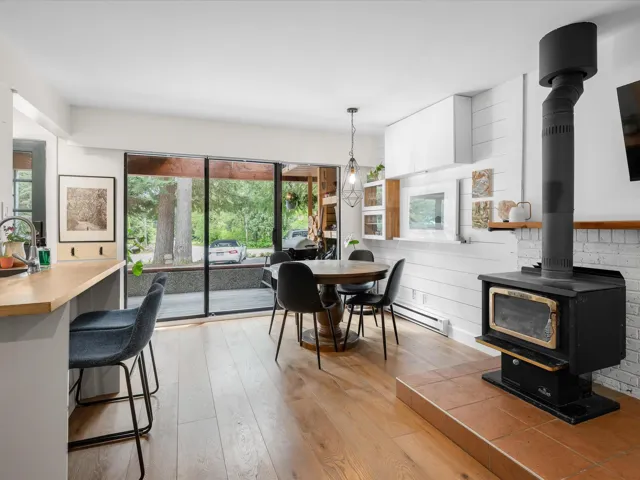 Dining area featuring a wood stove, light wood finished floors, plenty of natural light, and a baseboard radiator