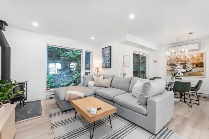 Living room with a wood stove, light wood-style flooring, recessed lighting, a baseboard radiator, and a chandelier