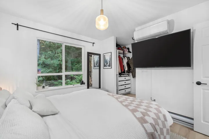 Bedroom with a wall mounted air conditioner, light wood-style flooring, and a baseboard radiator