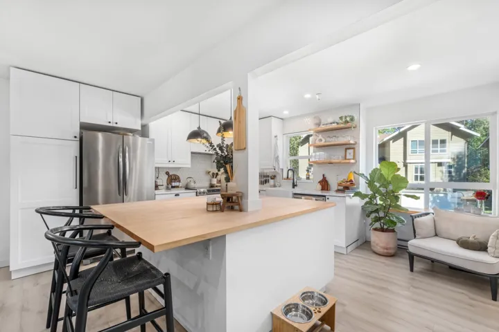 Kitchen with butcher block counters, white cabinets, backsplash, a kitchen bar, and light wood-style floors