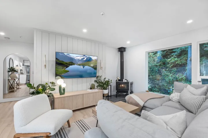 Living room featuring a wood stove, wood finished floors, recessed lighting, and wooden walls