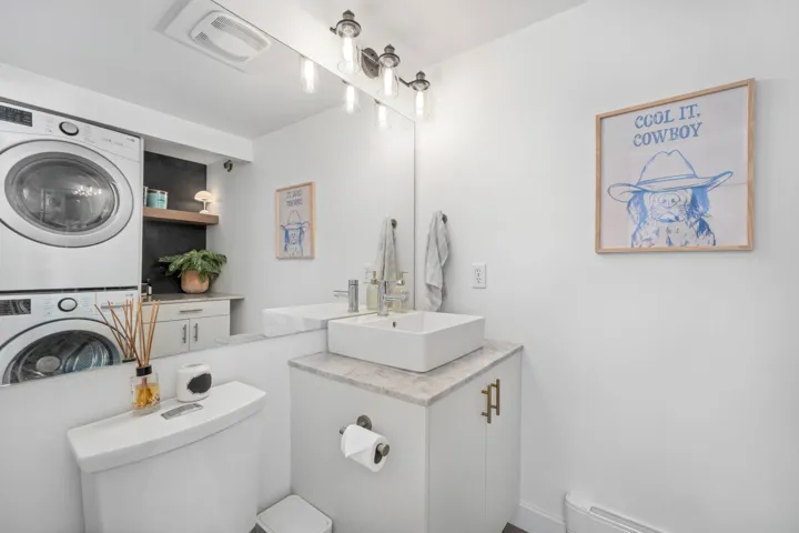 Half bath with vanity, estacked washer and dryer, and a baseboard radiator