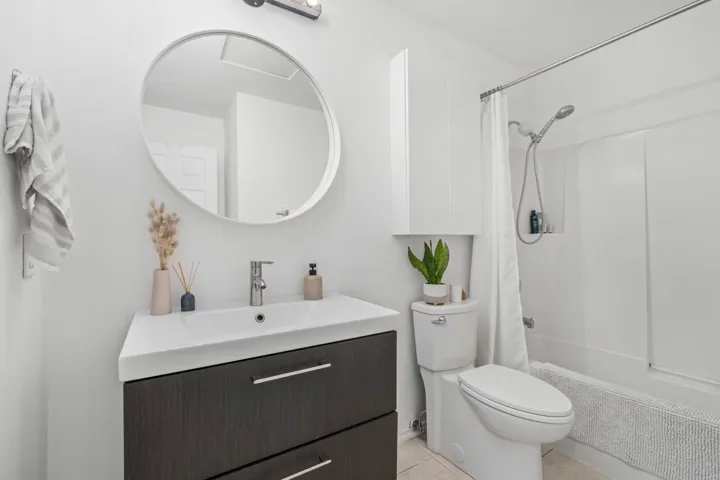 Full bath featuring vanity, shower / bath combo with shower curtain, and light tile patterned floors