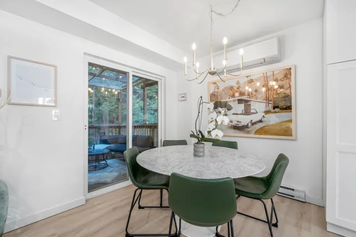 Dining area with light wood finished floors, a chandelier, a baseboard radiator, and an AC wall unit