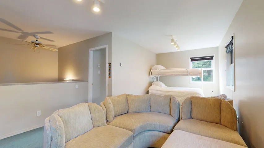 Living room with track lighting, carpet flooring, and ceiling fan