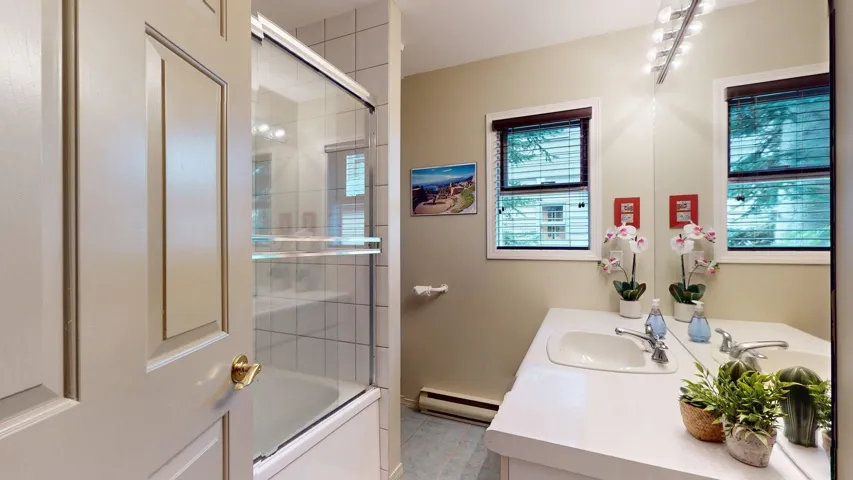 Full bath with vanity, bath / shower combo with glass door, and a baseboard radiator