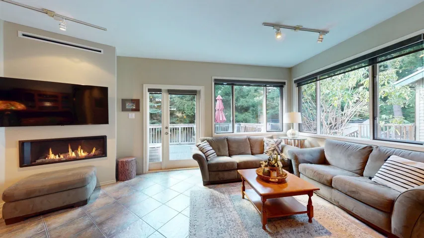 Living room with track lighting, a glass covered fireplace, and tile patterned flooring