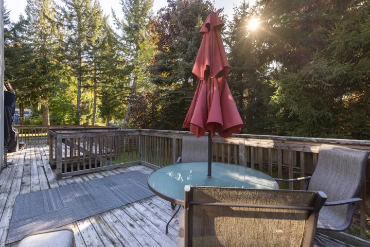 Wooden terrace with outdoor dining area and view of scattered trees