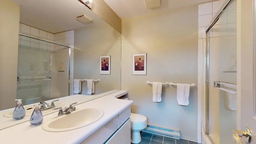 Bathroom with dark tile patterned floors, vanity, a stall shower, and a baseboard heating unit
