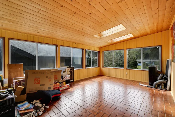 Sunroom / solarium featuring a vaulted wooden ceiling, a skylight, and wooden walls