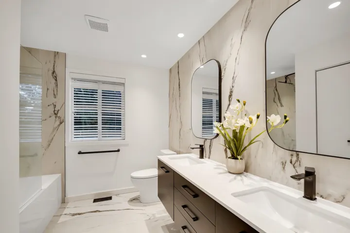 Full bathroom featuring stone wall, light marble finish floors, recessed lighting, and double vanity