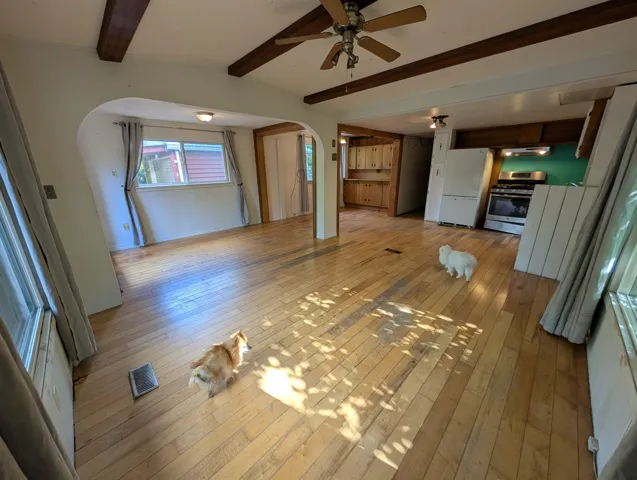 Open concept living area with exposed ceiling beams and wood-finish flooring