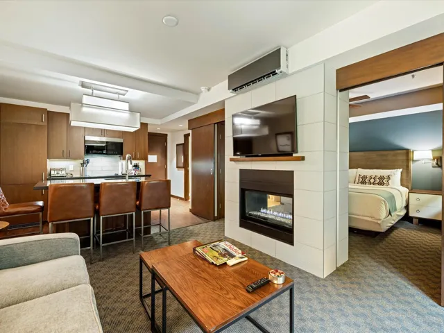 Living area featuring a wall mounted air conditioner, a tiled fireplace, and dark carpet