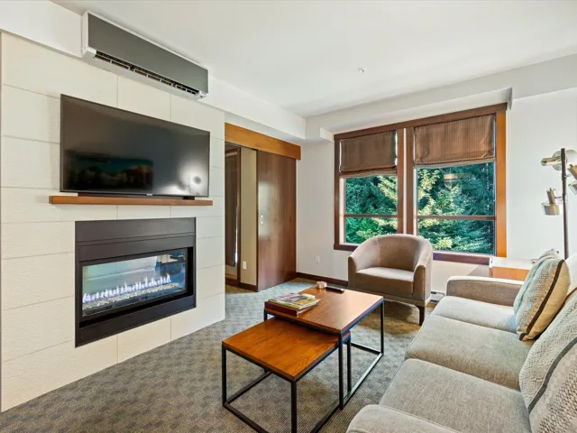 Living area featuring a glass covered fireplace, a wall mounted air conditioner, and carpet floors