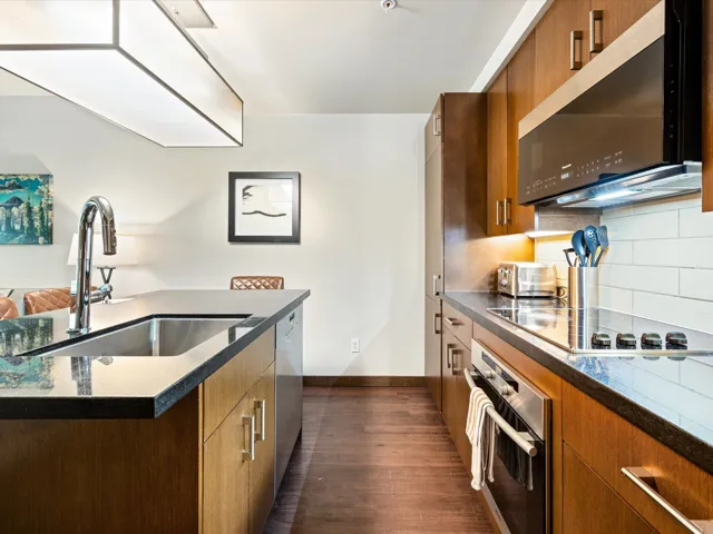 Kitchen with appliances with stainless steel finishes, brown cabinets, dark wood-type flooring, decorative backsplash, and modern cabinets